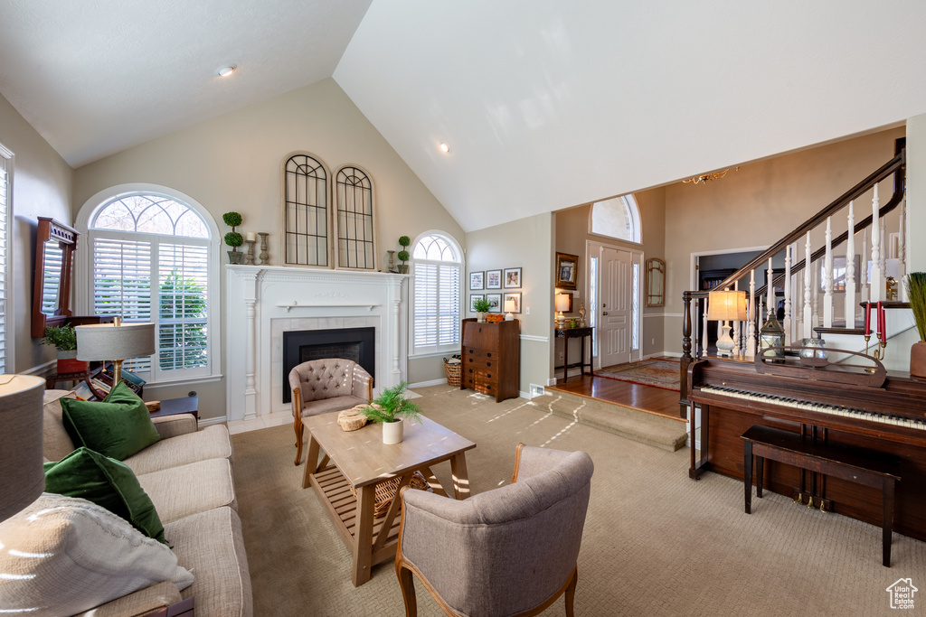 Living room featuring a tiled fireplace, light carpet, and high vaulted ceiling
