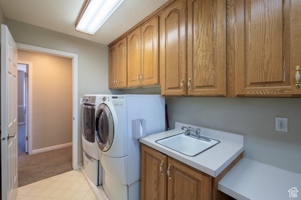 Washroom with light carpet, independent washer and dryer, sink, and cabinets