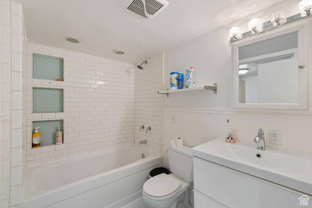 Full bathroom featuring tiled shower / bath combo, oversized vanity, and toilet