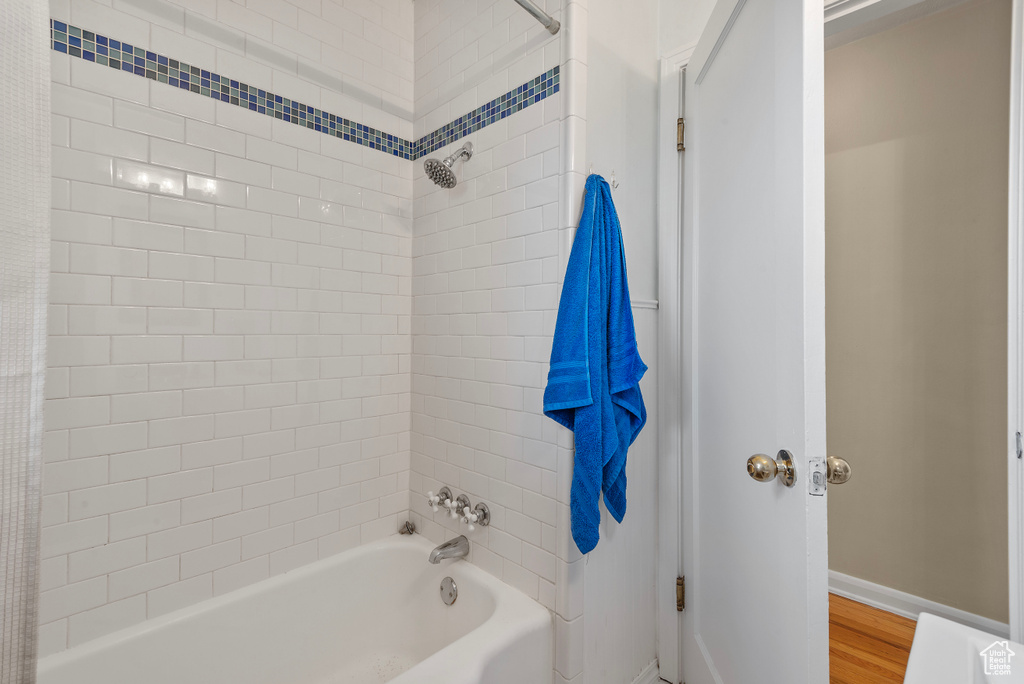 Bathroom with hardwood / wood-style flooring and tiled shower / bath