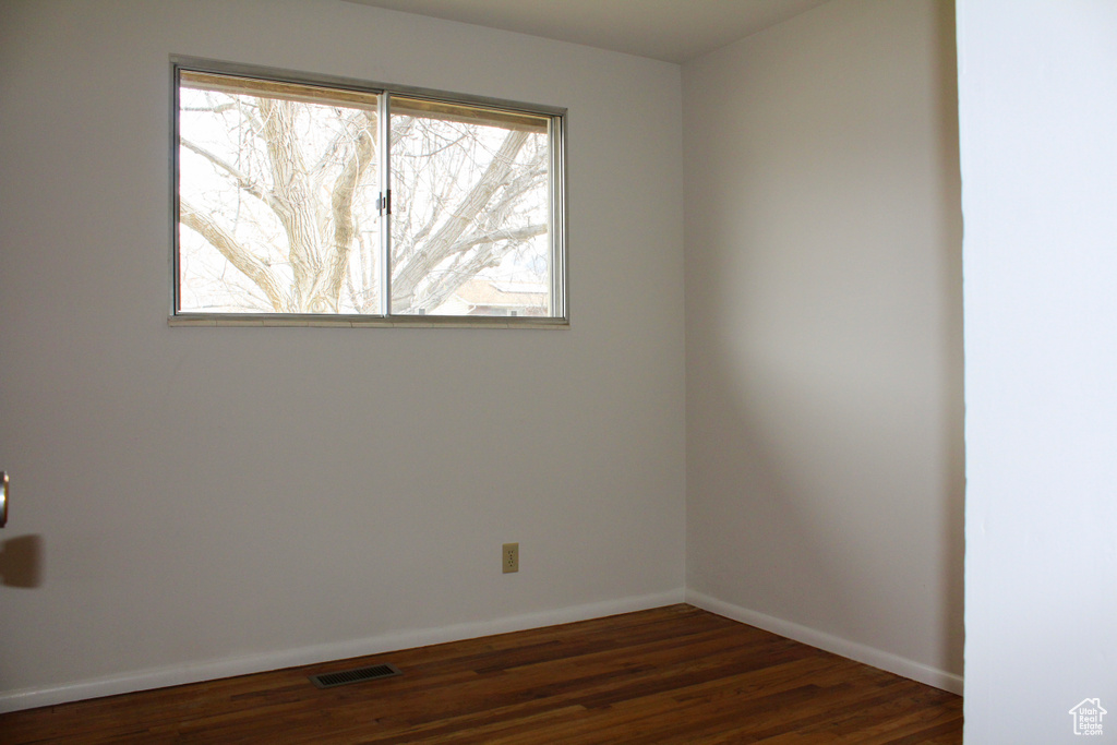 Empty room featuring dark hardwood / wood-style flooring and a healthy amount of sunlight