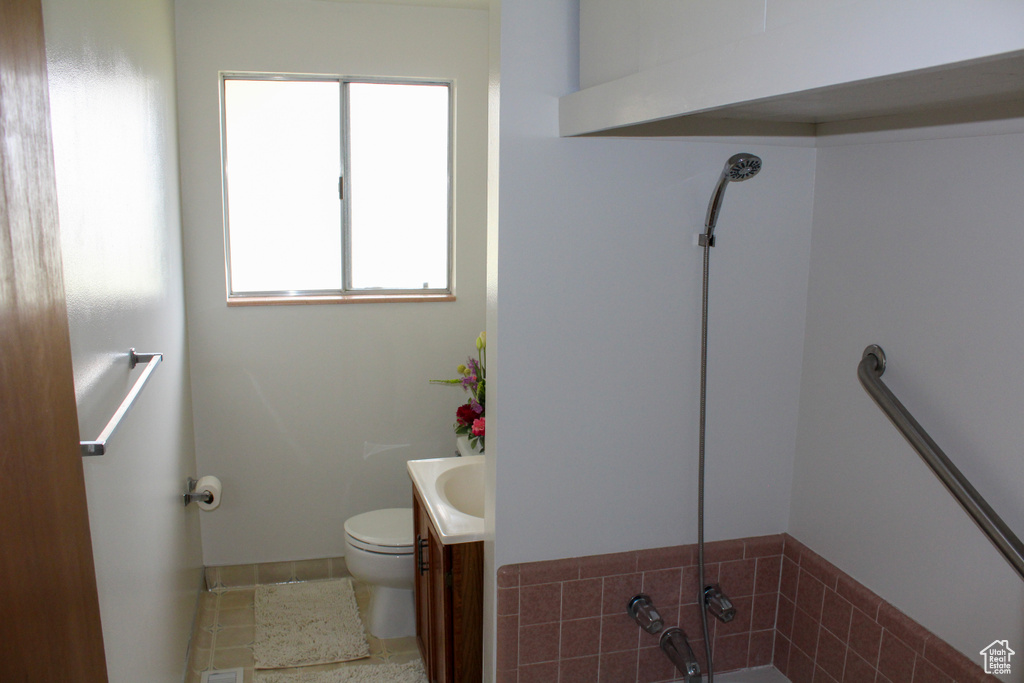 Bathroom with vanity, toilet, tile flooring, and a wealth of natural light