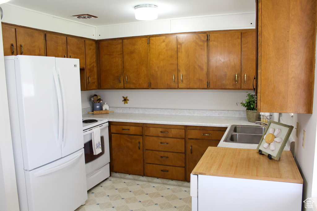 Kitchen with sink, white appliances, and light tile flooring