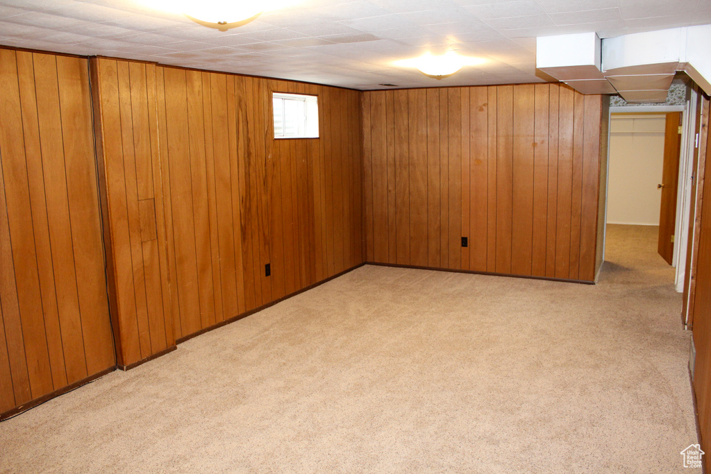Basement featuring light carpet and wooden walls