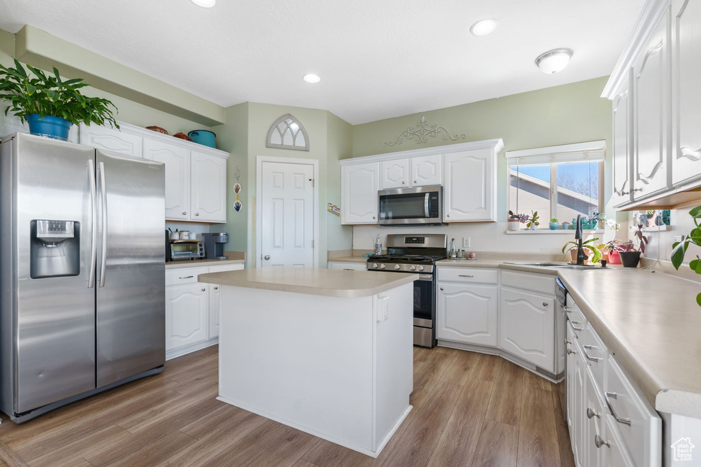 Kitchen featuring white cabinets, a kitchen island, light hardwood / wood-style flooring, and stainless steel appliances