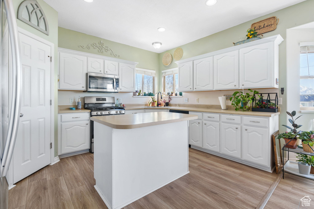Kitchen featuring appliances with stainless steel finishes, white cabinets, and light hardwood / wood-style floors