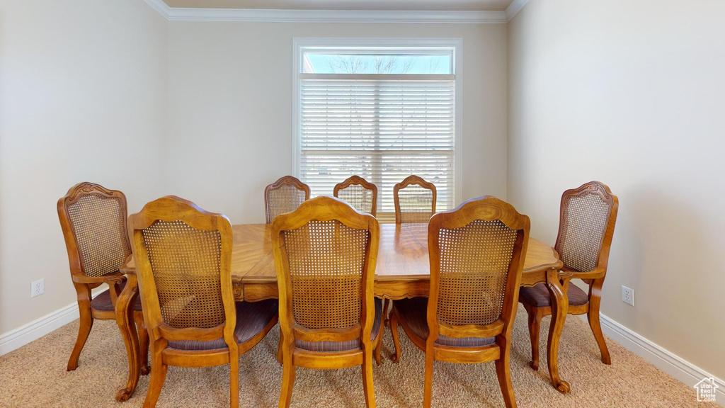 Dining space featuring light carpet and crown molding