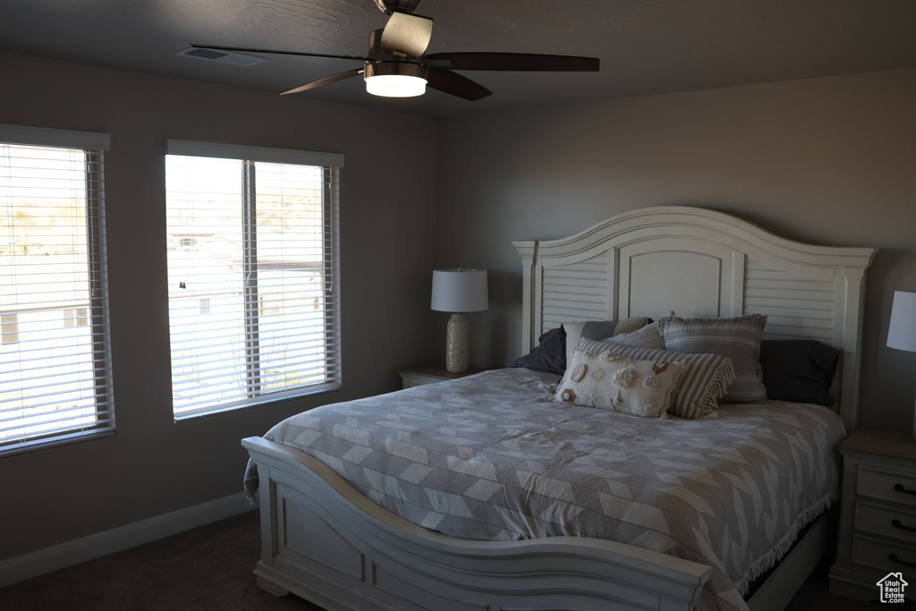 Bedroom featuring multiple windows, dark carpet, and ceiling fan
