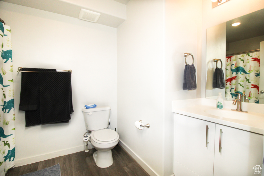 Bathroom with large vanity, toilet, and hardwood / wood-style flooring