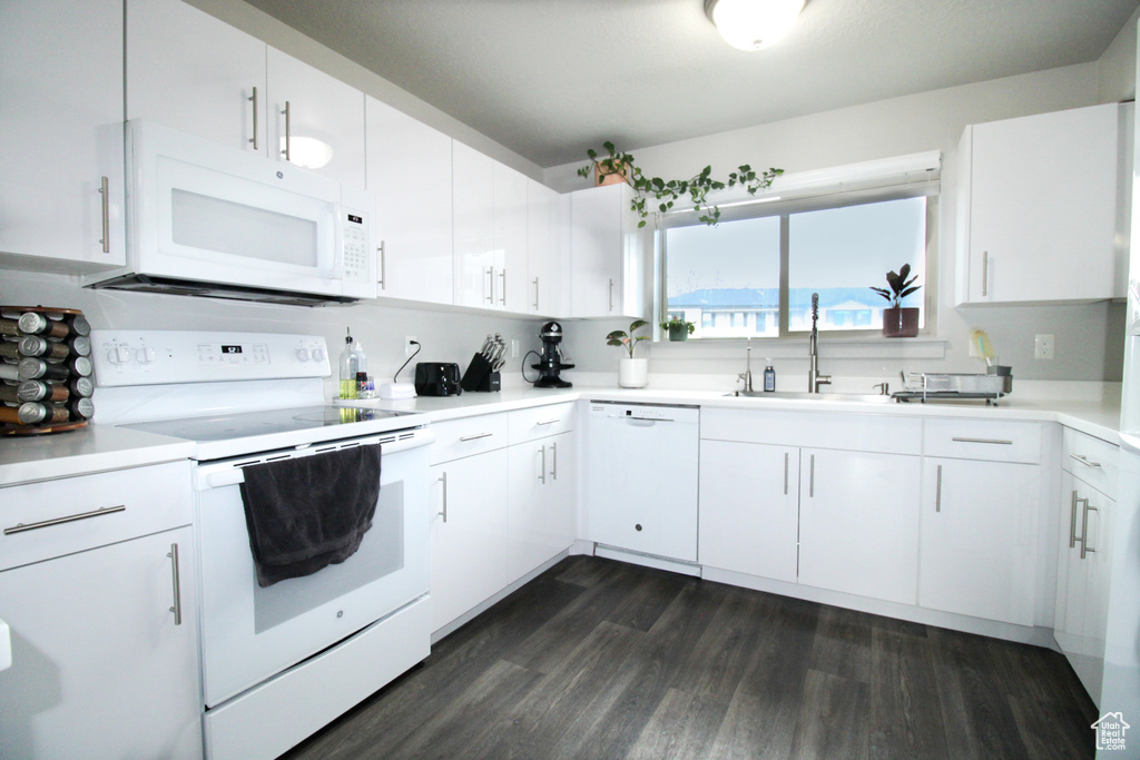 Kitchen with sink, white appliances, dark hardwood / wood-style floors, and white cabinetry