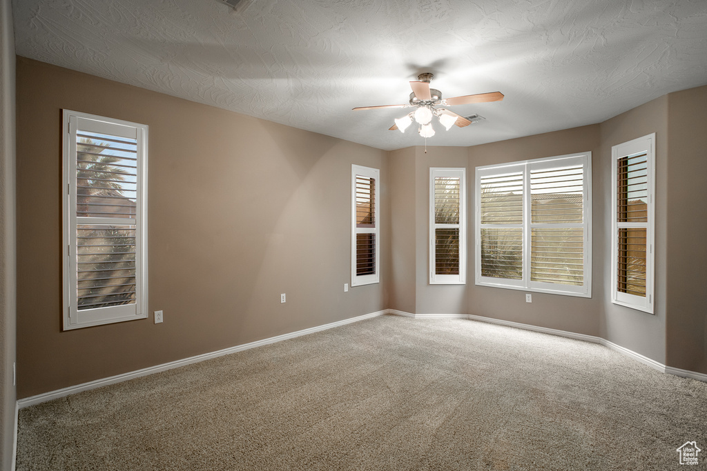 Unfurnished room with a textured ceiling, carpet flooring, and ceiling fan