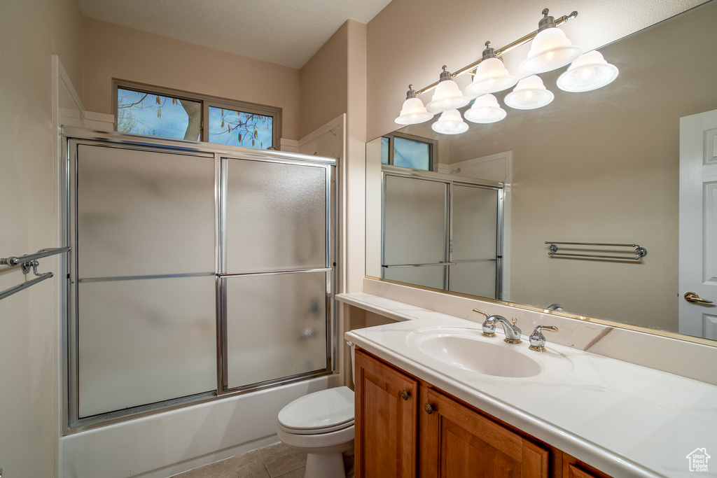 Full bathroom featuring vanity, toilet, shower / bath combination with glass door, and tile floors