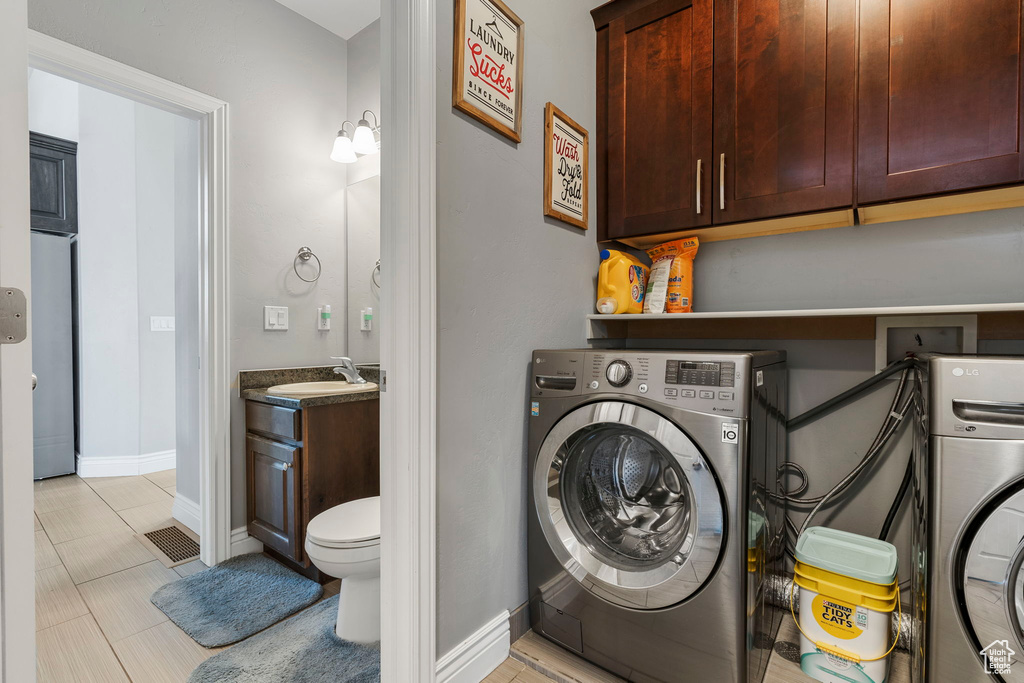 Laundry area featuring sink, light tile floors, and washer / dryer