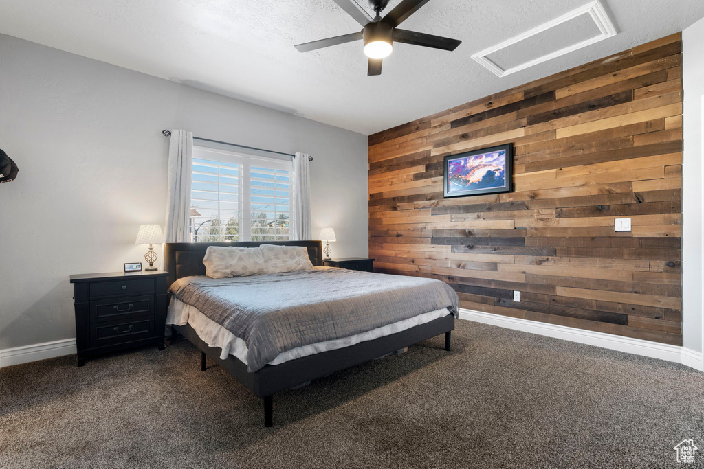 Carpeted bedroom with ceiling fan and wooden walls