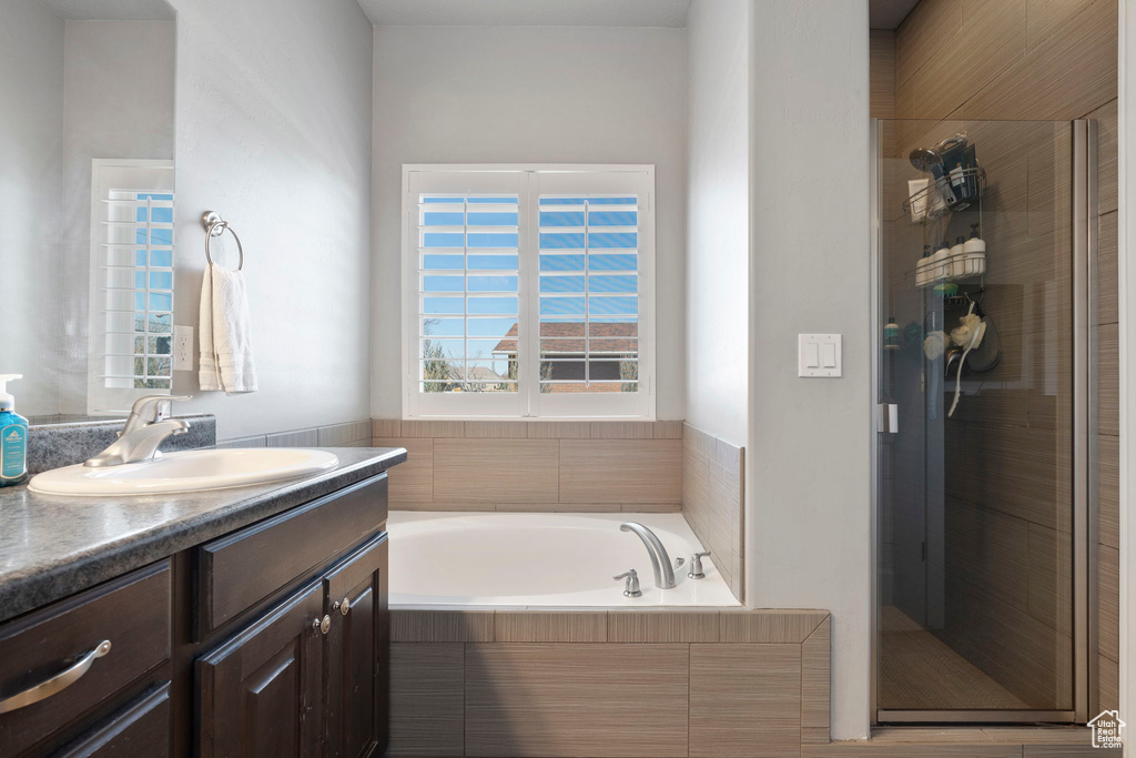 Bathroom featuring plus walk in shower and vanity with extensive cabinet space