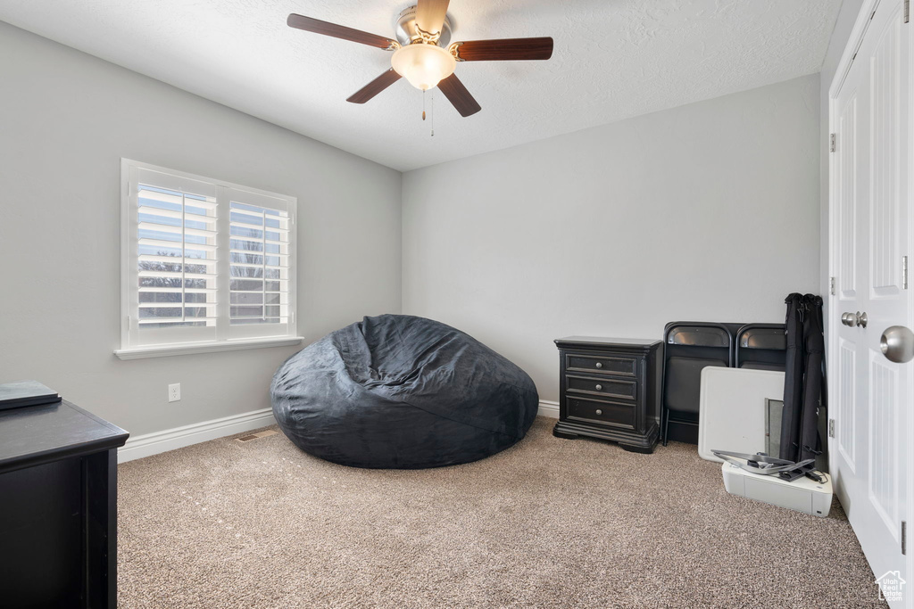 Interior space with ceiling fan, a textured ceiling, and light colored carpet