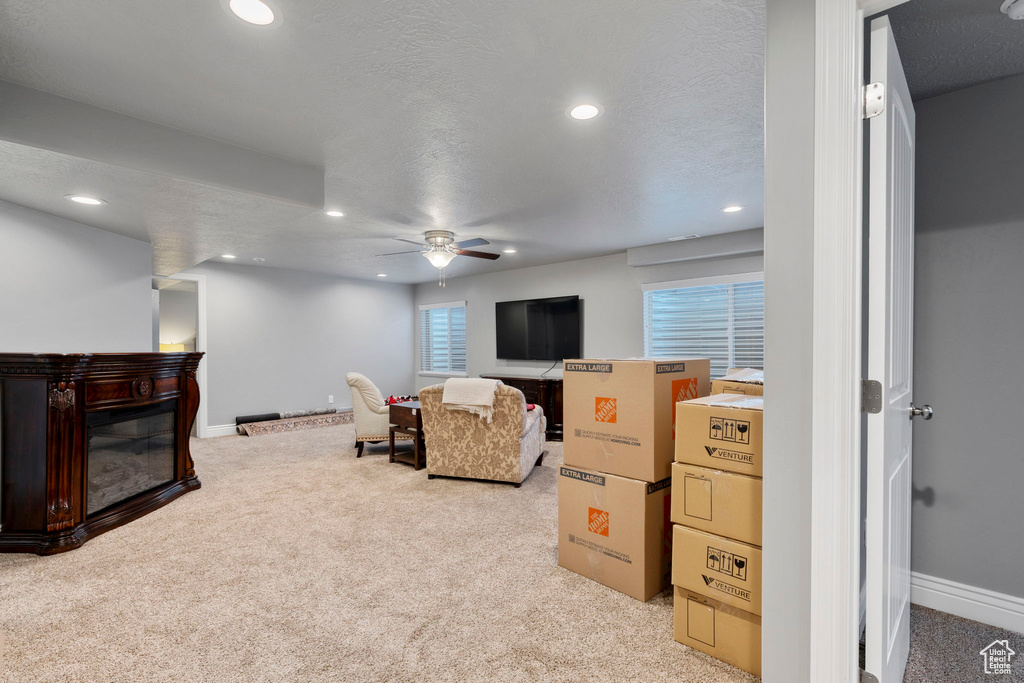 Living room with light colored carpet, a textured ceiling, and ceiling fan
