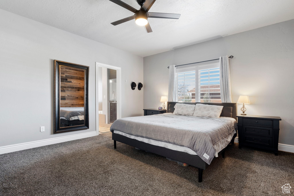 Bedroom with dark colored carpet, ensuite bath, and ceiling fan
