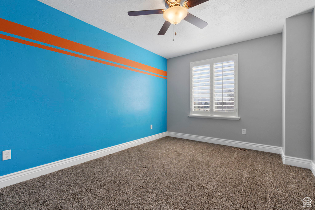 Carpeted spare room with ceiling fan and a textured ceiling