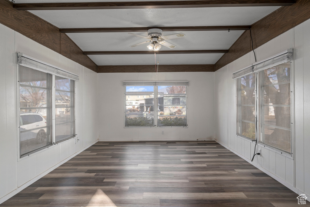 Unfurnished room featuring vaulted ceiling with beams, ceiling fan, and dark hardwood / wood-style floors