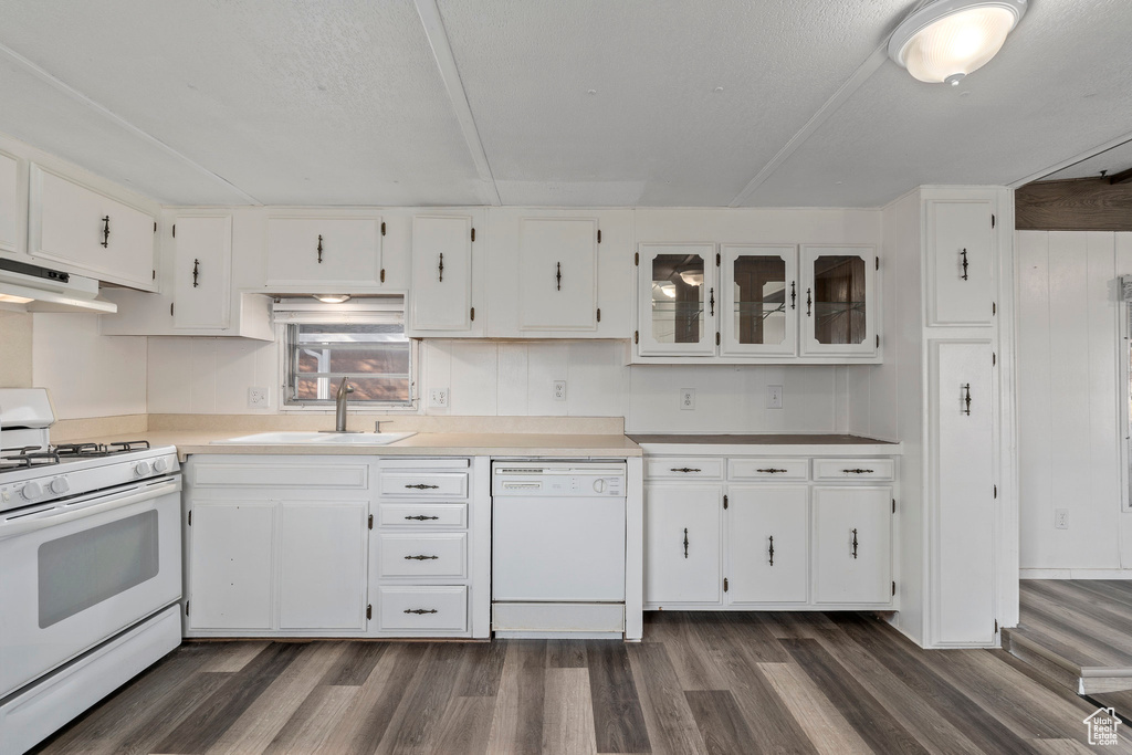 Kitchen with dark wood-type flooring, white cabinets, white appliances, and sink