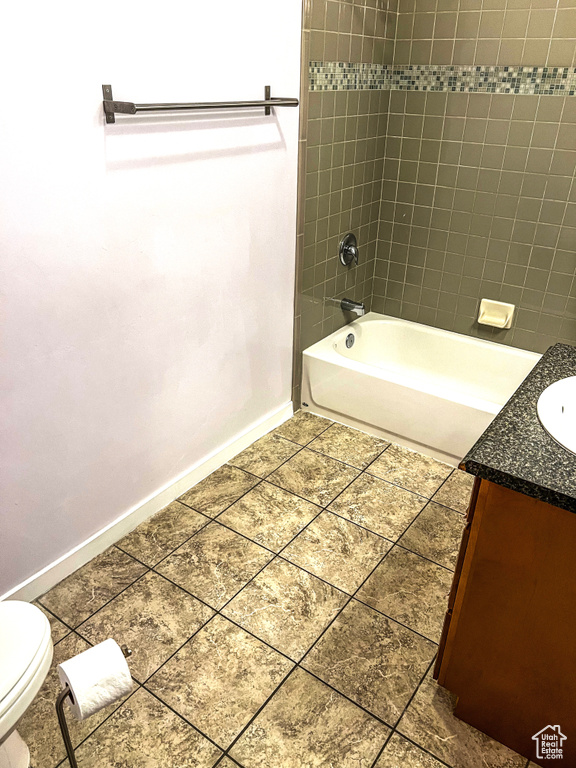 Full bathroom featuring tiled shower / bath combo, vanity, toilet, and tile floors