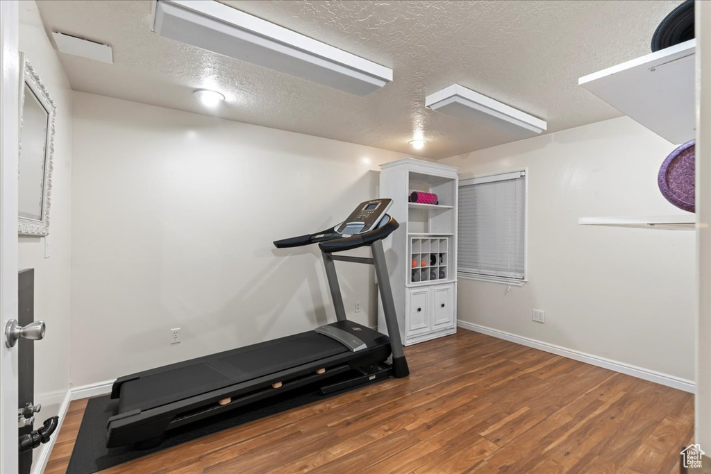 Exercise area featuring a textured ceiling and hardwood / wood-style floors