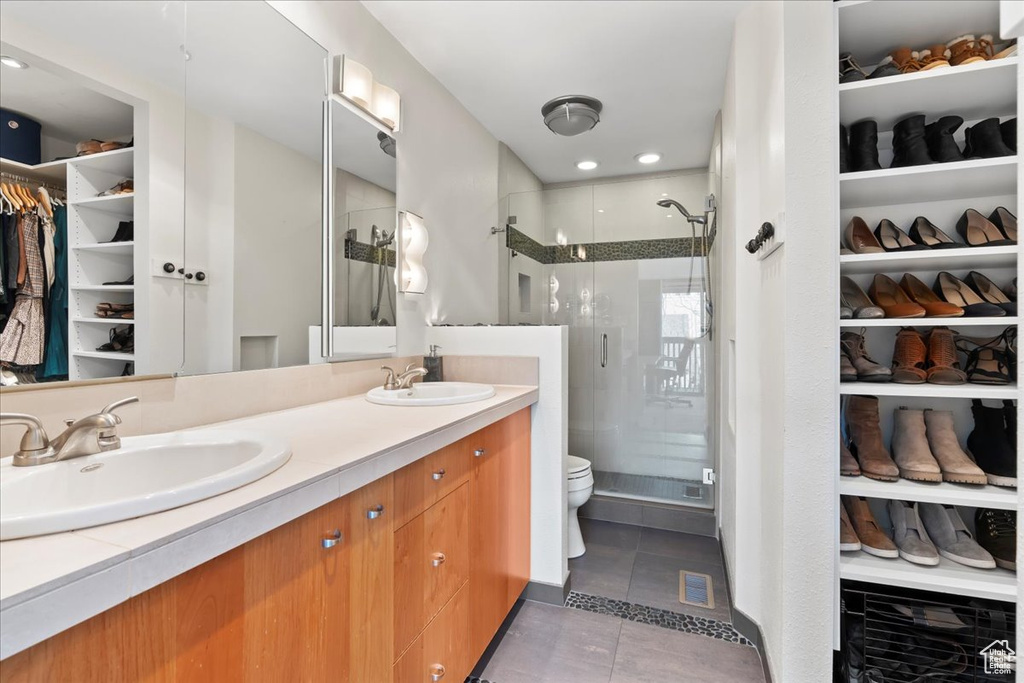 Bathroom featuring dual sinks, a shower with shower door, tile floors, oversized vanity, and toilet