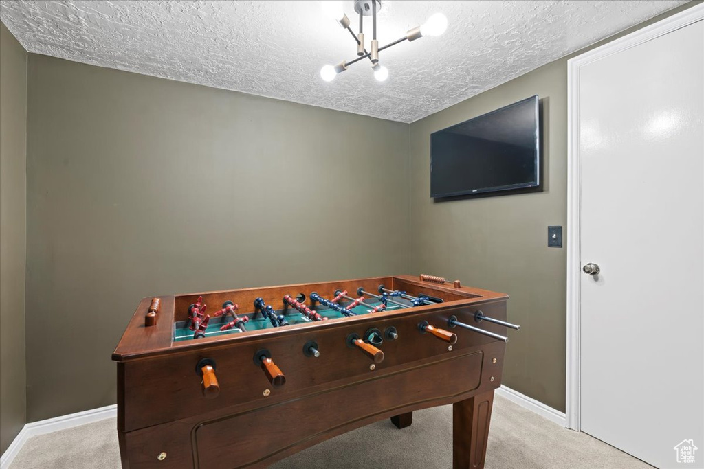 Game room featuring an inviting chandelier, light colored carpet, and a textured ceiling