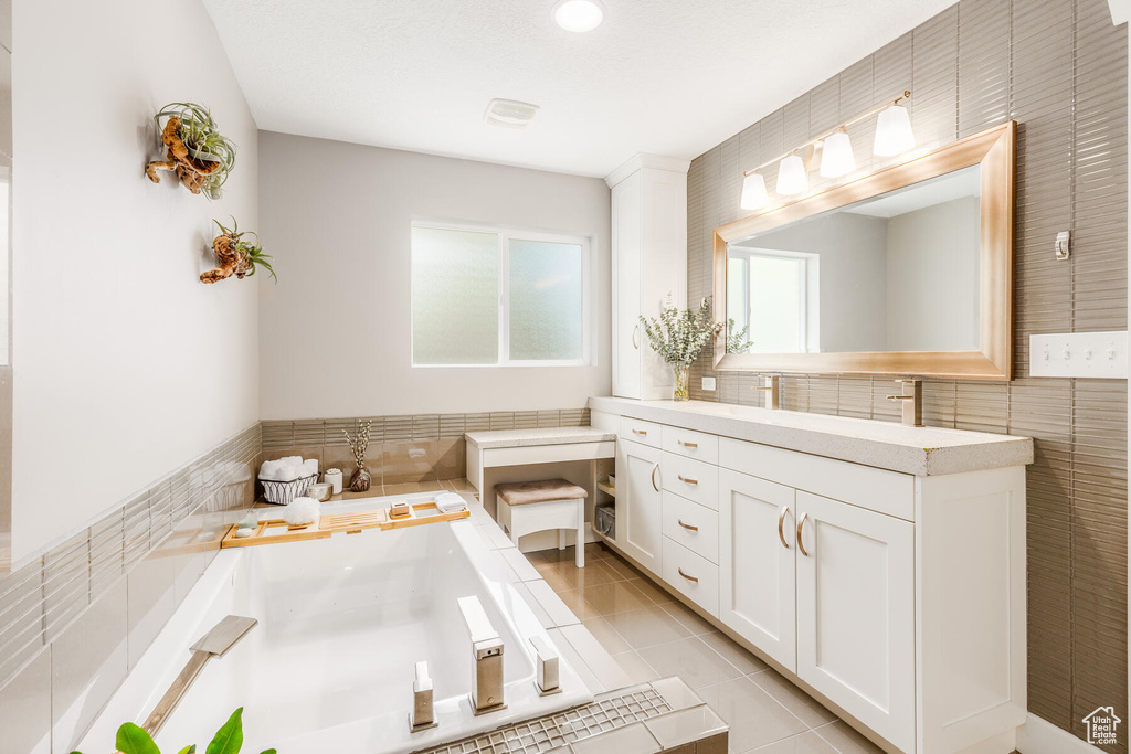 Bathroom featuring tile walls, backsplash, tile floors, a bathtub, and vanity