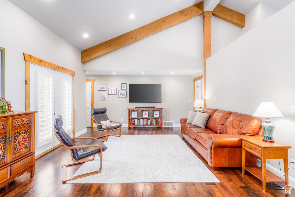 Living room with a healthy amount of sunlight, dark hardwood / wood-style floors, and beamed ceiling