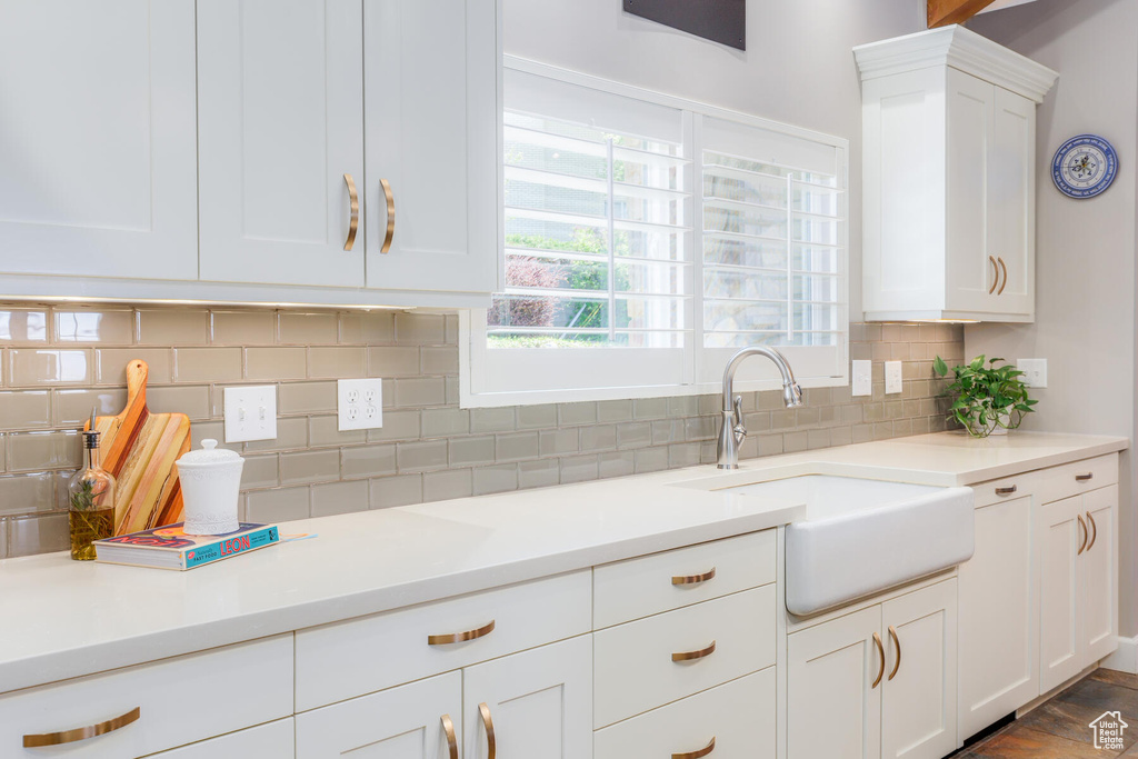 Kitchen featuring sink, backsplash, and white cabinetry