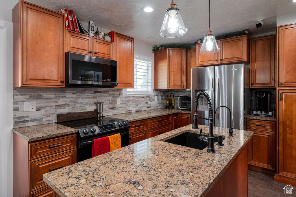 Kitchen featuring appliances with stainless steel finishes, sink, decorative light fixtures, and tasteful backsplash