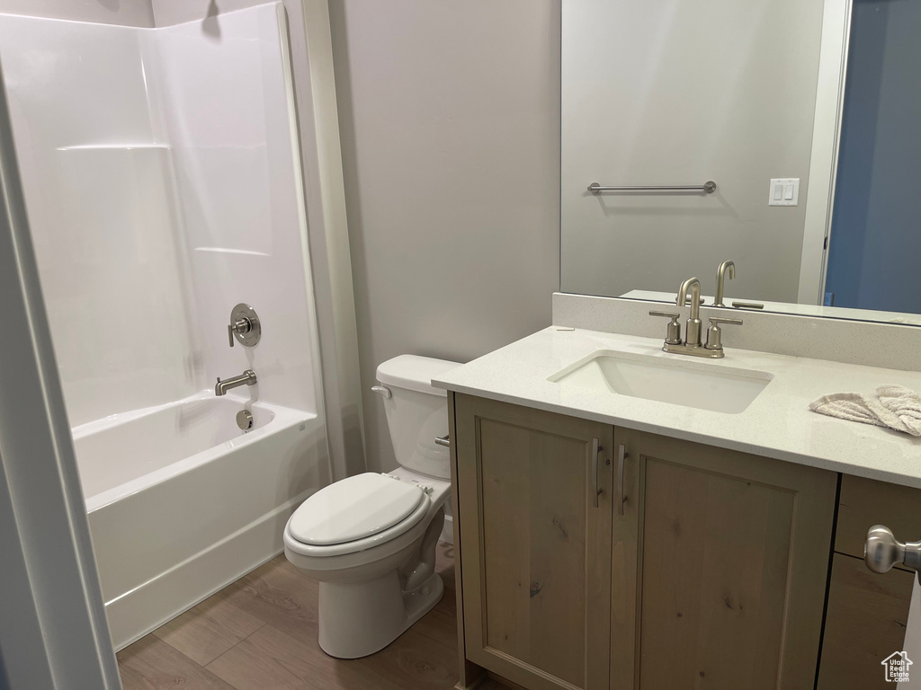 Full bathroom with shower / bathing tub combination, hardwood / wood-style flooring, toilet, and oversized vanity