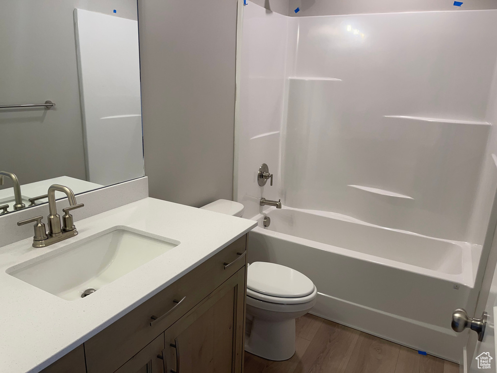 Full bathroom featuring washtub / shower combination, hardwood / wood-style floors, vanity, and toilet