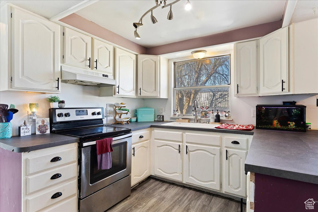 Kitchen featuring hardwood / wood-style flooring, sink, white cabinets, and stainless steel electric range
