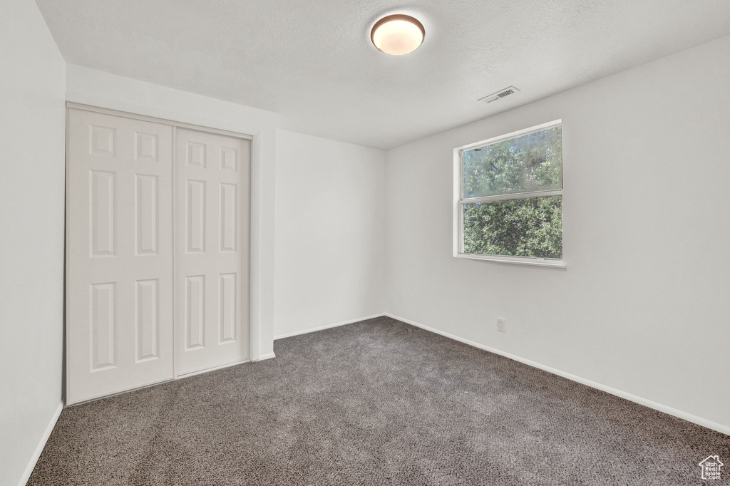 Unfurnished bedroom featuring dark colored carpet and a closet