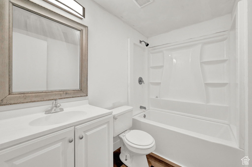 Full bathroom with shower / bath combination, oversized vanity, hardwood / wood-style flooring, and toilet