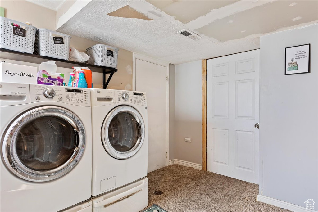 Washroom featuring a textured ceiling, light carpet, and washer and dryer