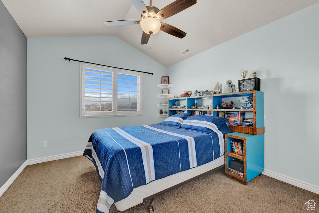 Carpeted bedroom with ceiling fan and lofted ceiling