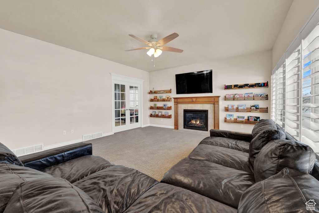 Living room featuring a fireplace, ceiling fan, and carpet floors