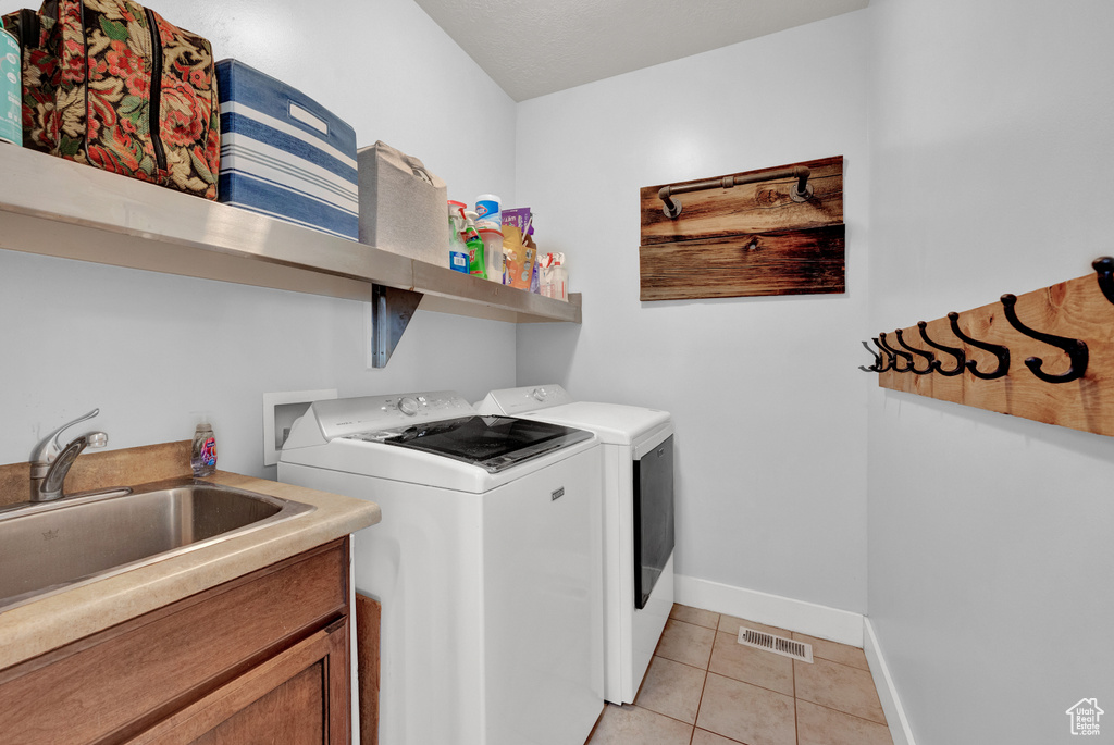 Laundry area featuring sink, washer and dryer, and light tile flooring