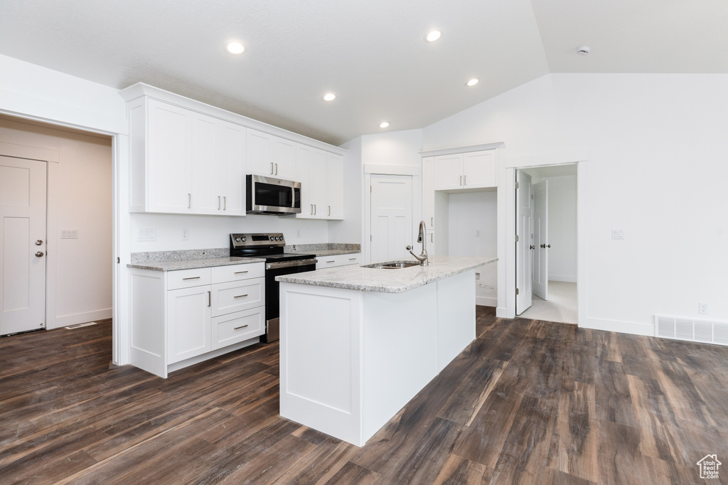Kitchen featuring dark hardwood / wood-style flooring, appliances with stainless steel finishes, white cabinetry, and a kitchen island with sink