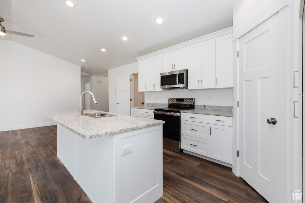Kitchen featuring appliances with stainless steel finishes, white cabinets, sink, dark hardwood / wood-style floors, and a kitchen island with sink