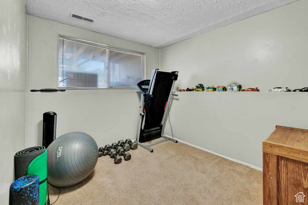 Workout area with light carpet and a textured ceiling