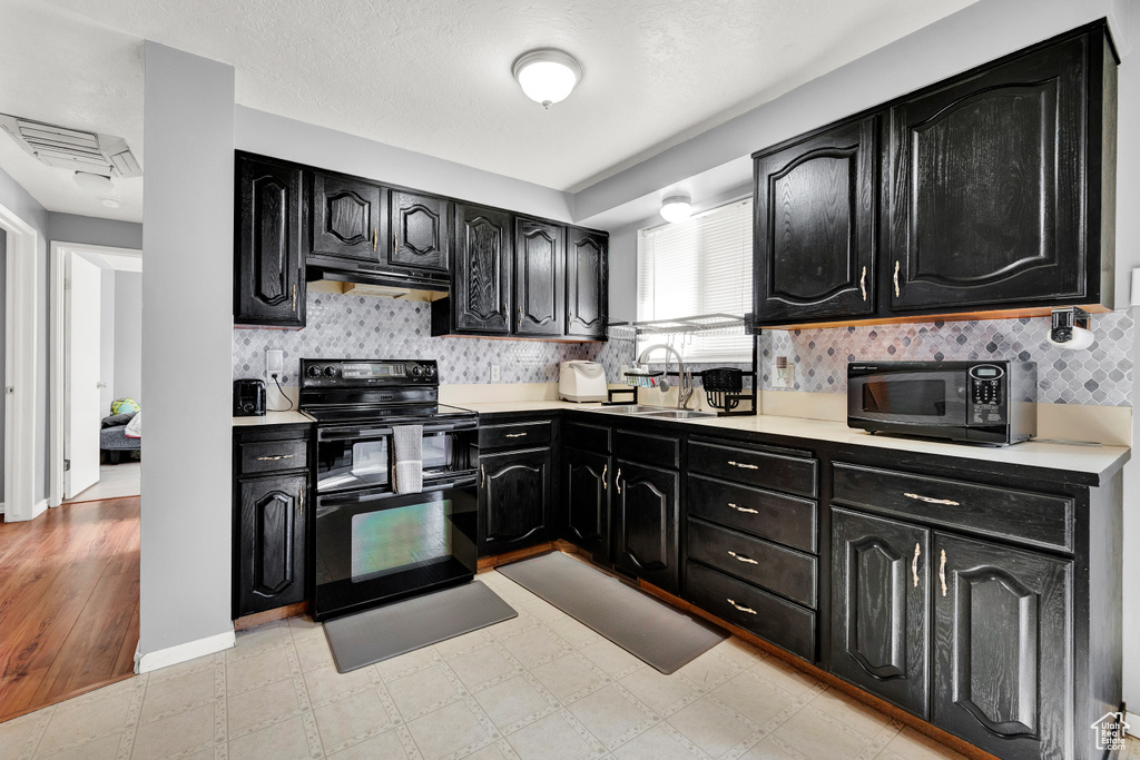 Kitchen with black appliances, sink, backsplash, and light tile flooring
