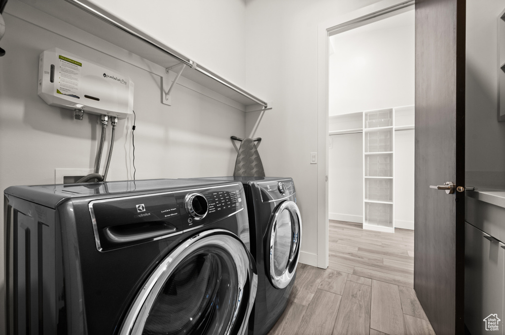 Clothes washing area with light hardwood / wood-style floors, washing machine and dryer, and hookup for a washing machine