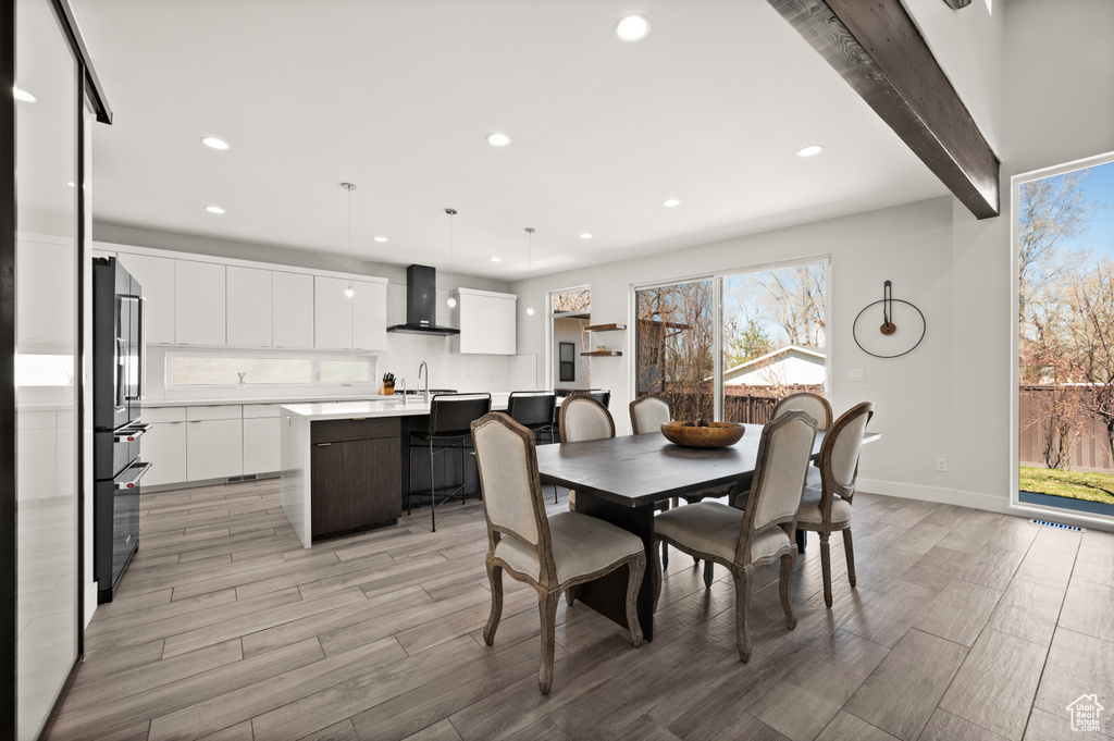 Dining space with sink, beamed ceiling, and light hardwood / wood-style floors
