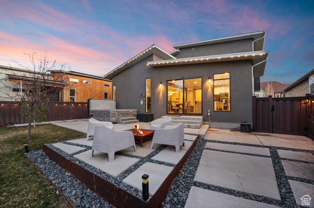 Back house at dusk with an outdoor hangout area and a patio