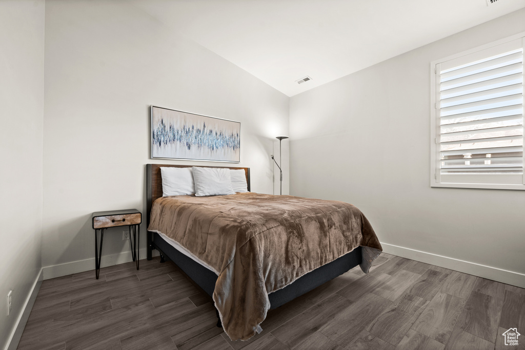 Bedroom featuring vaulted ceiling and dark hardwood / wood-style floors